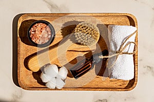 Natural cosmetics set in eco-friendly packaging in wooden tray with ctton flower and towel. SPA, bath beauty products