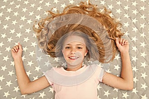 Natural curls treat and care. Girl child with long curly hair lay on bed top view. Child perfect curly hairstyle looks