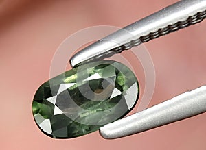 Natural dark green sapphire gem on the background