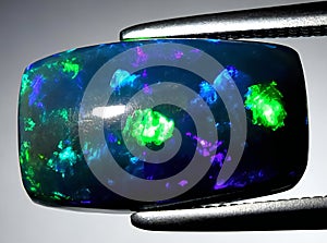 natural dark rainbow opal gem on the background