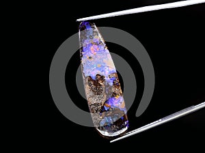 natural dark rainbow opal gem on the background