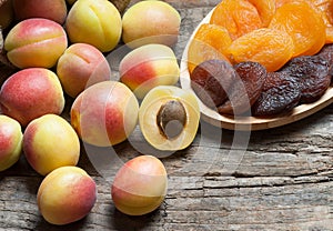 Natural dried apricots in bamboo bowl with Fresh whole Ripe apricot on wooden rustic backdrop