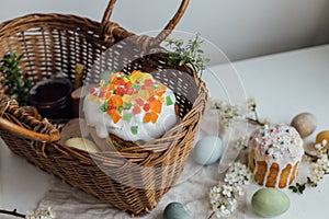 Natural dyed easter eggs, easter bread, ham, beets, butter, cheese in wicker basket decorated with green buxus on rustic wooden