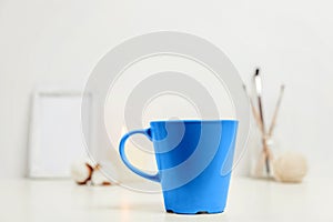 Natural eco home decor with cup coffee colored in trendy color of year 2020 Classic Blue near white workplace. Bright Macro color