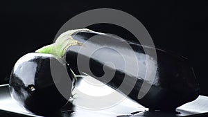 Natural eggplants gyrating on black background. Solanum Melongena