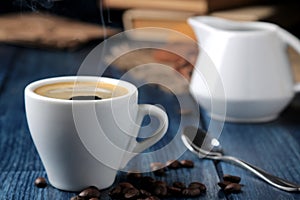 Natural espresso coffee in a ceramic coffee cup and coffee beans in the foreground on a blue wooden table