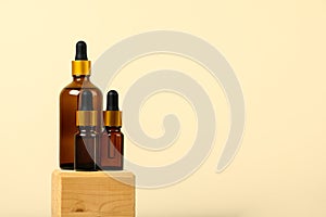 Natural essential oil, serum in a brown glass bottle with a pipette on a wooden podium with a copy space. Alternative medicine,