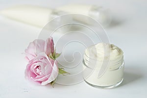 Natural face and body cream in a jar with a rose flower.