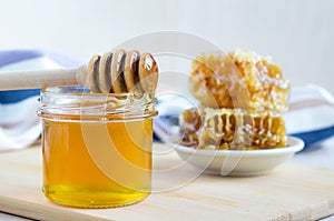 Natural flower honey in glass jar with dipper and honeycombs