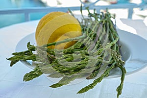 Natural food from forest and mountains in Greece green wild asparagus and lemon on balcony with sea view