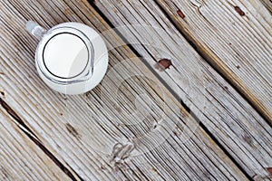 Natural food. A jug of cow milk on a wooden table, top view, closeup. Rustic style.
