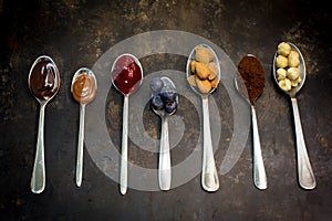 NATURAL FOOD PASTRY INGREDIENTS ON SPOONS, CHOCLATE, RASBERRIES, COCOA, ALMOND, STRAWBERRY photo