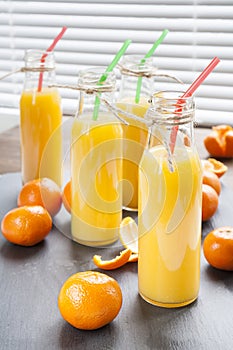 Natural and fresh orange juice in small bottles with fresh tangerine (mandarin)