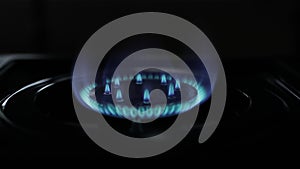 Natural gas blue fire flame on kitchen burner gas stove on dark background. Circular gas-jet. Flame Gas Burner Operation