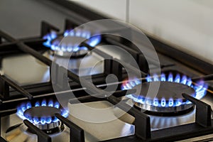 Natural gas burning on kitchen gas stove in the dark. Panel from steel with a gas ring burner on a black background, close-up shoo