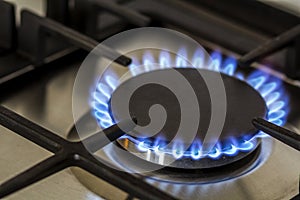 Natural gas burning on kitchen gas stove in the dark. Panel from steel with a gas ring burner on a black background, close-up shoo