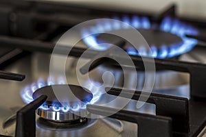 Natural gas burning on kitchen gas stove in the dark. Panel from steel with a gas ring burner on a black background, close-up shoo