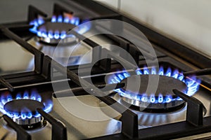 Natural gas burning on kitchen gas stove in the dark. Panel from steel with a gas ring burner on a black background, close-up shoo photo