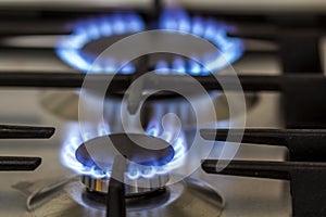 Natural gas burning on kitchen gas stove in the dark. Panel from steel with a gas ring burner on a black background, close-up shoo