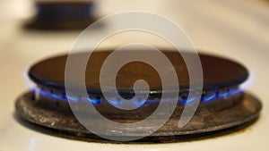 Natural gas burning on white enameled domestic stove at kitchen. Close up of natural gas flames in gas stove on the