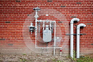 Natural gas meter gauge and pipeline on the red brick wall