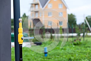 Natural gas pipeline with a closed tap on the background of a cottage