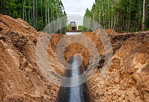 Natural Gas Pipeline Construction. Dozer on earthworks while laying a gas pipe in a green area