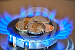 Natural gas prices concept. Blue flames and Euro coins on hob