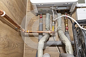 Natural gas valves and pipes in a modern home boiler room with ceramic tiles..