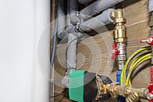 Natural gas valves and pipes in a modern home boiler room with ceramic tiles, visible water circulating pump.