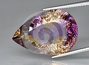 Natural gemstone colored ametrine in thongs on a gray background. Natural Bolivian bicolor yellow purple ametrine