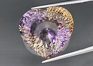 Natural gemstone colored ametrine in thongs on a gray background. Natural Bolivian bicolor yellow purple ametrine