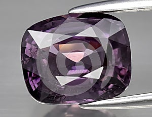 Natural gemstone purple spinel on gray background