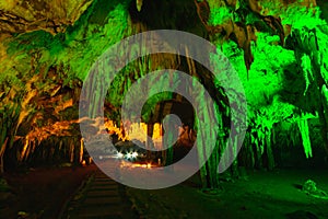 natural gray stalagmite or stalactite with green and red led light in dark cave in mountain