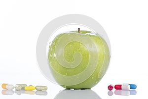 Natural green apple and various pills on white