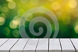 Natural green background with selective focus. The green background has a bokeh leaf and grass on a white wooden floor.