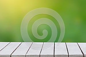 Natural green background with selective focus. The green background has a bokeh leaf and grass on a white wooden floor. Empty tabl