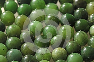 Natural green jade nephrite mineral stones beads. Green and grassy natural background made of round stone beads