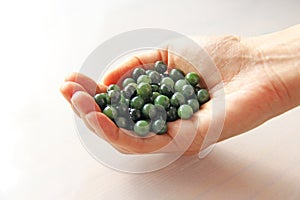 Natural green jade nephrite mineral stones beads. The green jade stone lies in the hands. Hands holding stone on white background