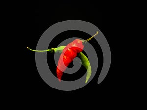 Natural green and red chilies on a dark background.