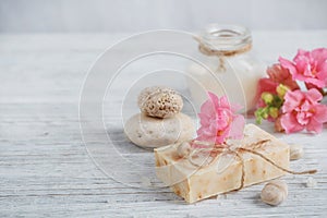 Natural handmade soap, aromatic oil and flowers on white wooden