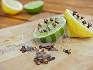 Natural homemade repellents on wooden table. Lime and lemon with cloves