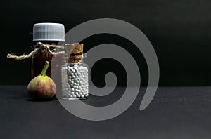 Natural Homeopathic medicine concept - Homeopathic medicine bottles with wild fruit on dark background photo