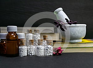 Natural Homeopathy Concept Ã¢â¬â Healing herbs in a mortar and pestle next to homeopathic medicine consisting a bottle of pills- photo