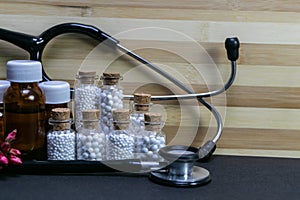 Natural Homeopathy Concept - A Stethoscope with Homeopathic medicine bottles consisting pills and liquid substance and pink flower