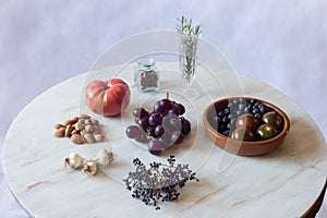 Natural ingredients on an antique marble table, a rustic bowl, and glass jars set with a branch of privet.