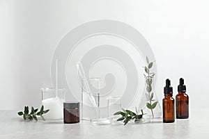 Natural ingredients for cosmetic products and laboratory glassware on white table