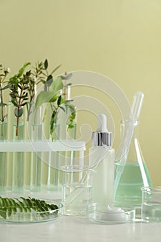 Natural ingredients for cosmetic products and laboratory glassware on white table