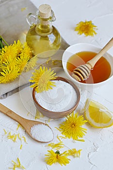 Natural ingredients for homemade body salt scrub with dandelion flowers, lemon, honey and olive oil