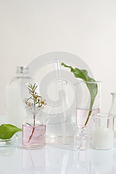 Natural ingredients and laboratory glassware for organic cosmetic product on white table